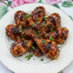 Baked BBQ Chicken Drumsticks on a white plate with sticky glaze and browned edges