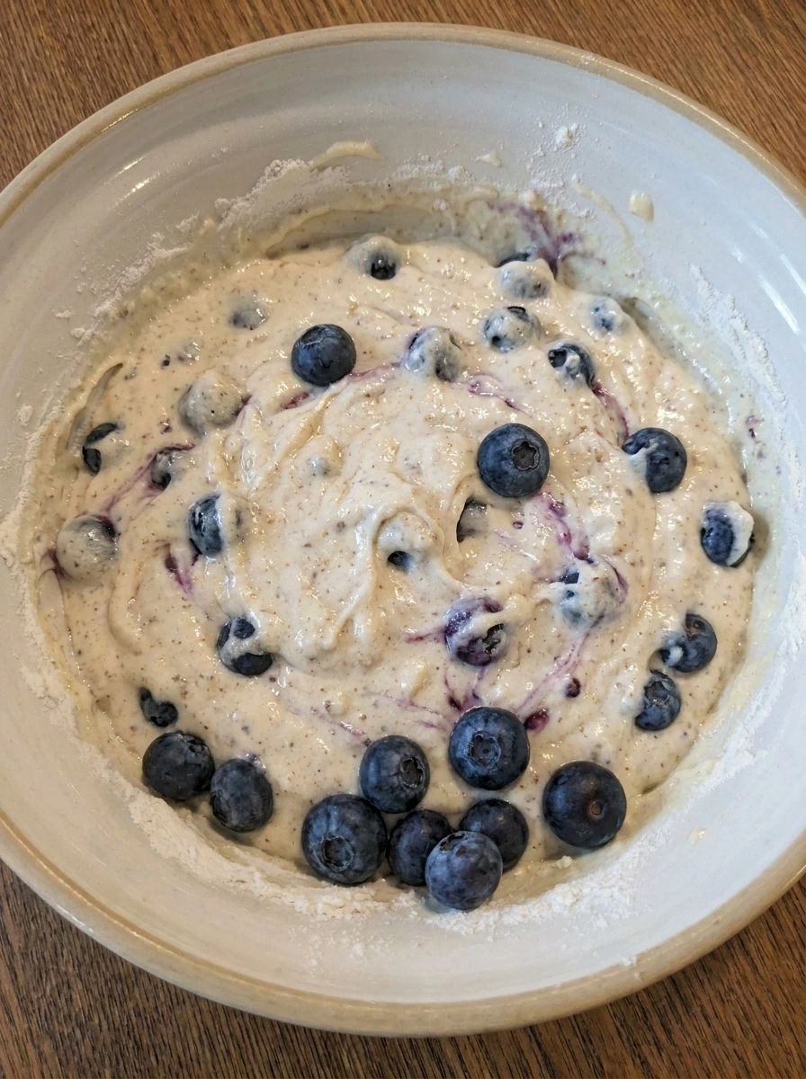 Blueberries folded into thick muffin batter