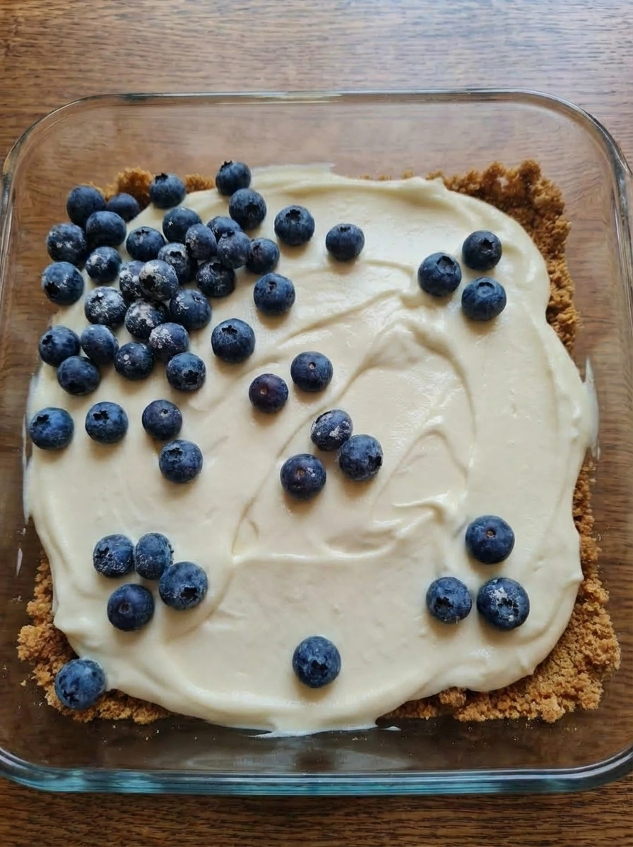 Blueberries scattered over cream cheese filling before baking