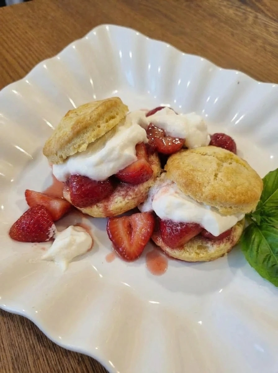Classic Strawberry Shortcake on a white scalloped dessert plate with juicy strawberries and whipped cream
