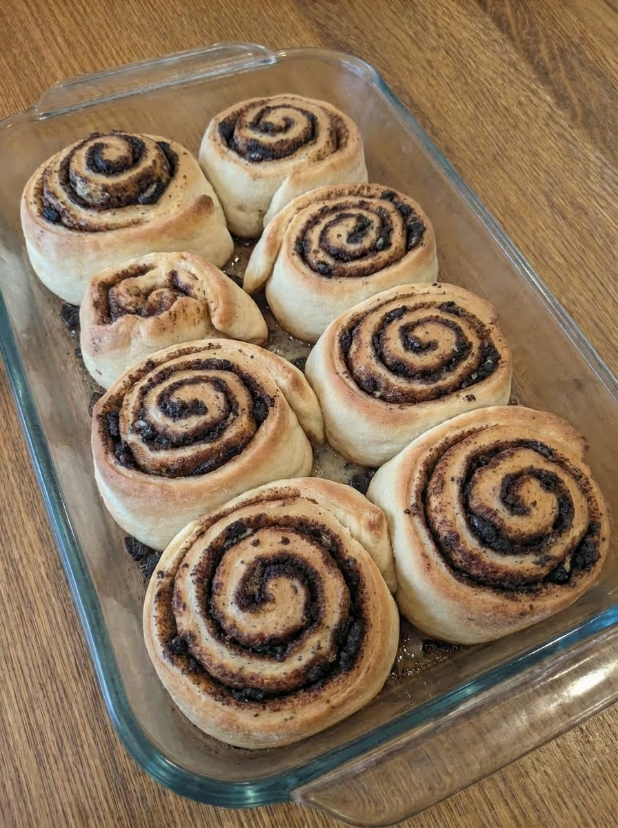 Baked cookies and cream cinnamon rolls puffed and lightly golden in a baking dish.