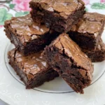 Fudgy Chocolate Brownies stacked on a white plate with crackly tops and soft centers