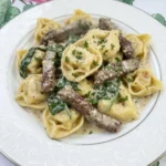 Garlic Steak Tortellini on a white plate with browned steak and creamy sauce