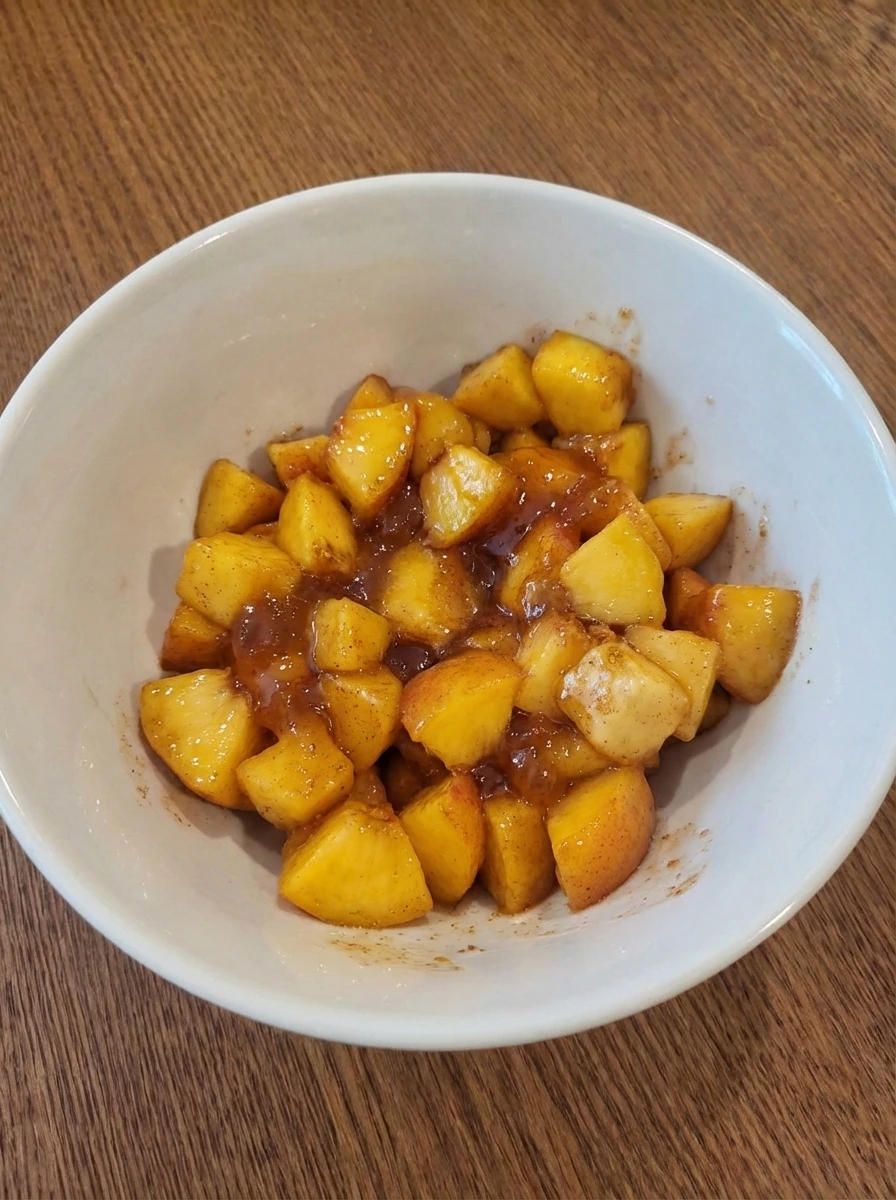 Diced peaches mixed with preserves and cinnamon in a white dish