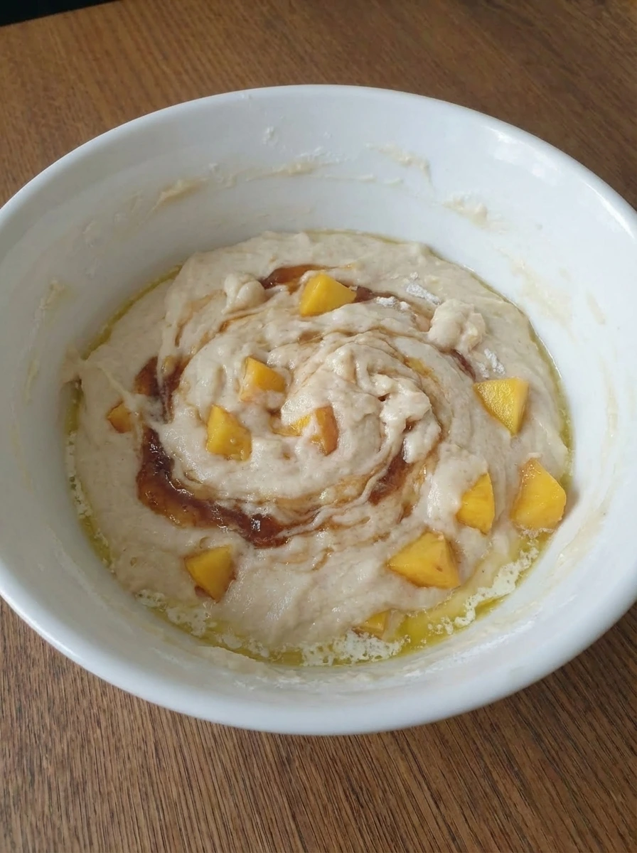 Peach biscuit batter poured over melted butter in a white dish