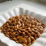 Honey Roasted Pumpkin Seeds with glossy amber honey-cinnamon coating in a white scalloped bowl Recipe focus: how to make honey roasted pumpkin seeds.