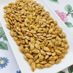 Lemon Roasted Pumpkin Seeds piled on a white platter with golden edges, paprika speckles and fresh lemon Recipe focus: how to make lemon roasted pumpkin seeds.
