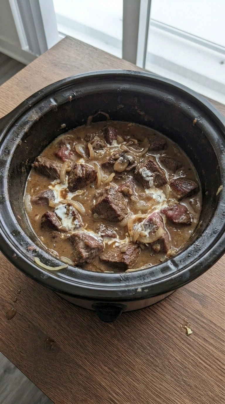 Crockpot Beef Stroganoff creamy sauce thickening around tender beef pieces Recipe focus: beef stroganoff crockpot.