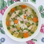 Crockpot Chicken and Rice Soup with shredded chicken, long-grain rice, carrots and peas in a white bowl Recipe focus: chicken and rice soup crockpot.