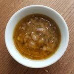Fall Salad Dressing with glossy amber vinaigrette, softened shallot and thyme in a small white bowl Recipe focus: fall salad dressing recipes.