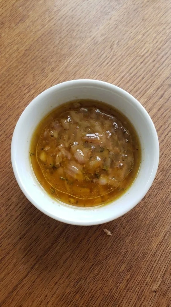Fall Salad Dressing with glossy amber vinaigrette, softened shallot and thyme in a small white bowl Recipe focus: fall salad dressing recipes.