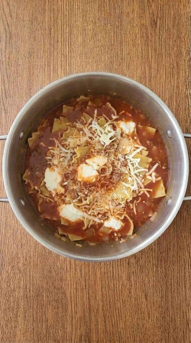 One Pot Lasagna Soup adding melted cheese into creamy tomato pasta broth Recipe focus: creamy lasagna soup.