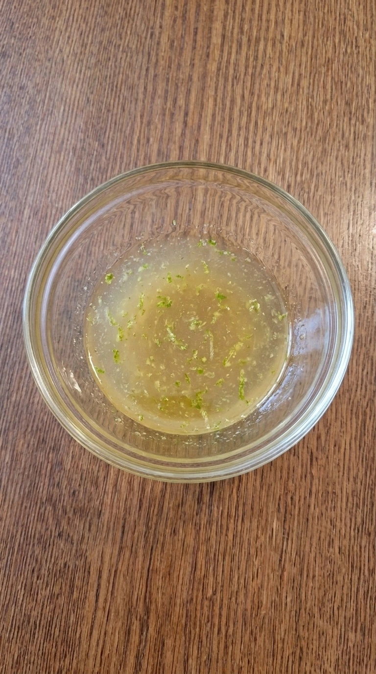Christmas Fruit Salad honey lime dressing mixed into a pale golden liquid with small green zest flecks Recipe focus: green christmas salad.