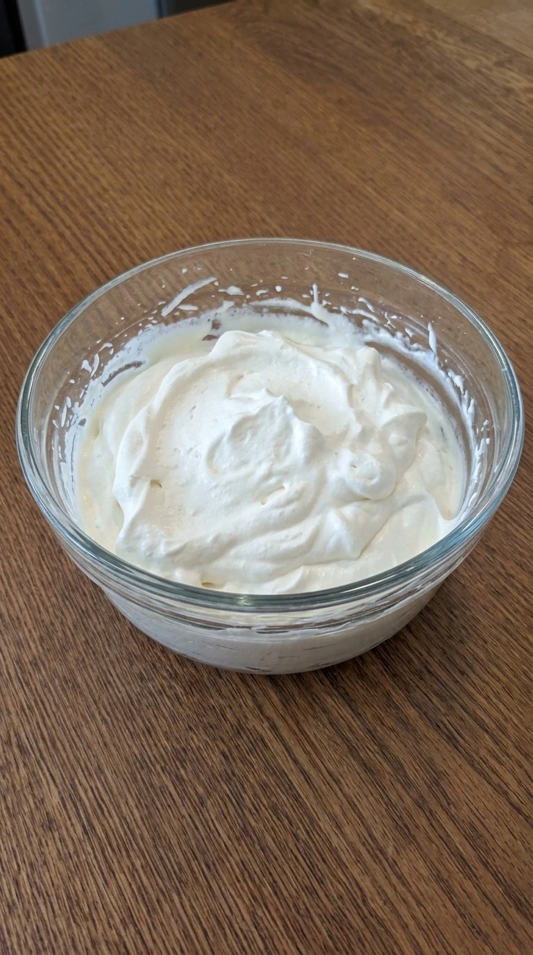Christmas Trifle whipped cream with soft white peaks and airy folds in a glass mixing bowl Recipe focus: christmas trifle holidays.